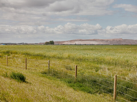 Prairie farmland with wire fence and mining piles in Saskatchewan, Can