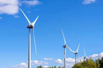 Blades of the windmill generating electricity on the background of blue cloudy sky, source renewable energy in the countryside.