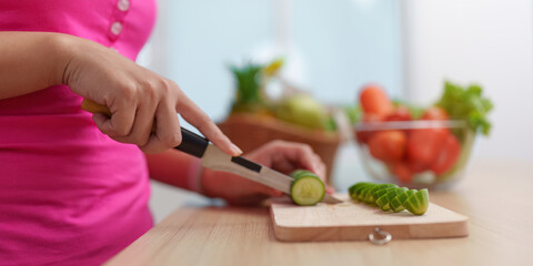 Healthy Meal Prep. Woman cutting cucumber slices for a nutritious dish.