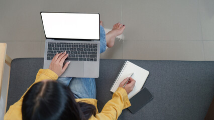 Lifestyle. Woman working on a laptop while taking notes in a cozy home environment.