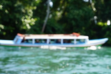 A wooden boat sails on a lake in a blurry photo