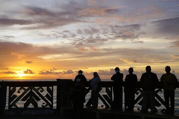 A number of tourists enjoy the beautiful sunset on the beach