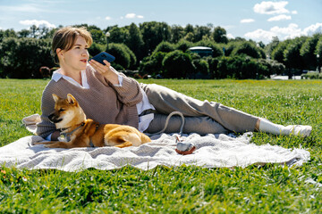 Woman recording voice message while lying on blanket with dog