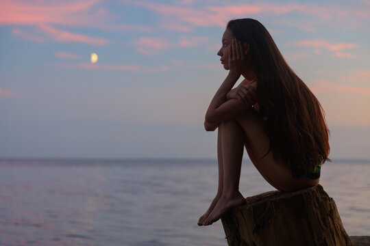 Reflective Moment by the Sea During Pink Sunset