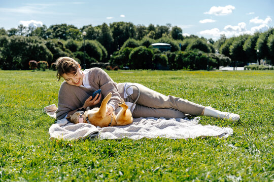 Woman relaxing on blanket while playing with puppy in park