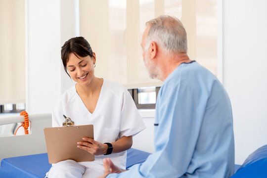 Nurse taking notes while talking with senior patient in hospital room