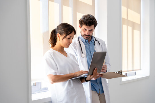 Doctor and nurse discussing patient information using laptop