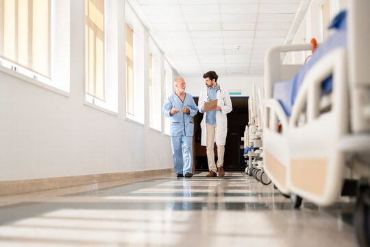 Doctor visiting patient walking in hospital corridor