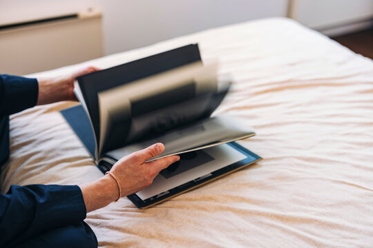 Person Flipping Through a Photo Album While Sitting on a Bed