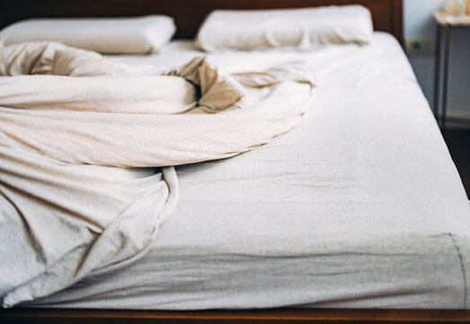 Unmade Bed with White Linens and Pillows in a Cozy Bedroom Setting
