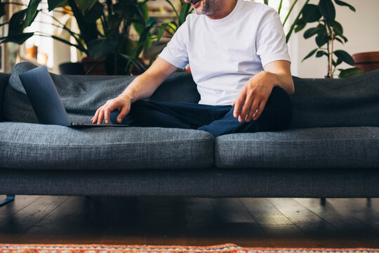 Man Relaxing at Home Using a Laptop on a Sofa