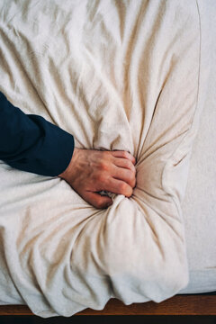 Close-Up of Hand Gripping Soft White Fabric on a Bed Surface