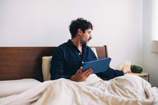 Man Holding Tablet in Bed with Emphasis on Morning Routine
