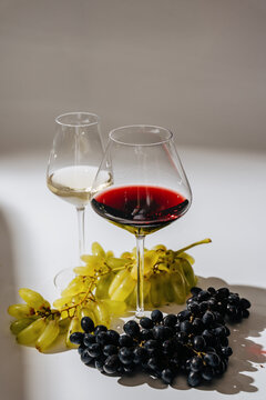 Red and white wine glasses with black and green grapes