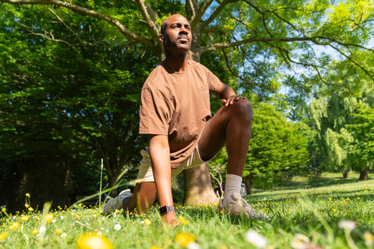 Black man performing a lunge in a London Park