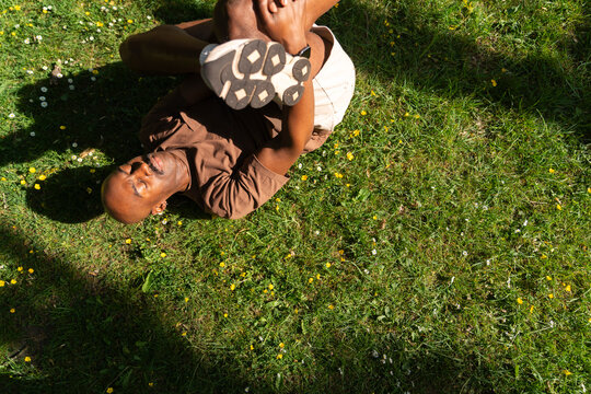 Yoga Male Teacher stretches his body on the grass of a London Park