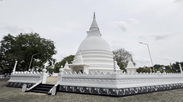 Buddhist temple in Sri Lanka with white pagoda under blue sky