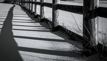 Snow-covered ground with long shadows cast by a wooden fence