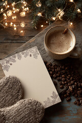Top view of a blank card with patterns and copy space, a cup of coffee, coffee beans and knitted mittens on a background of garlands
