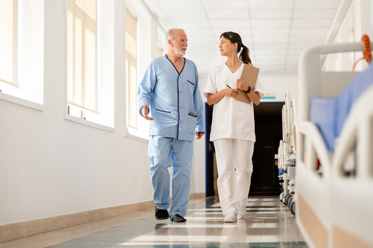 Nurse walking with senior patient in hospital corridor