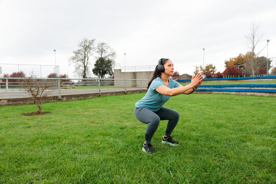 Woman performing squat exercise on grass field