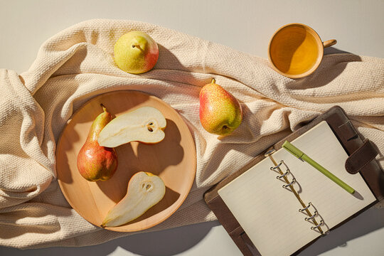 Pears, a notepad, and a cup arranged beautifully