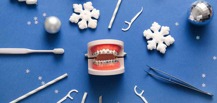 Composition with jaw model, dentist's tools and Christmas decorations on blue background