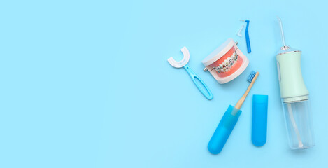 Jaw model with oral irrigator and toothbrushes on blue background