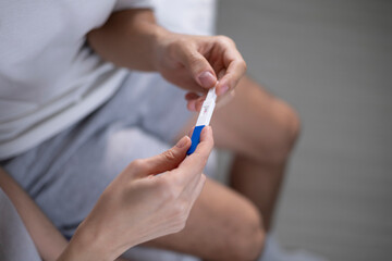 A happy couple with a pregnancy test result. It's a moment of joy and excitement and the joy of a man and woman on the bed for having a child, family and surprise.