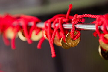 Row of five-yen coins tied with red string as talisman seen in a temple of Japan.