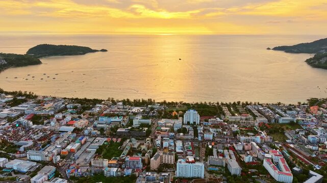 Aerial footage of Patong, Phuket, at sunset, showcasing the vibrant town, bustling beach, and sparkling Andaman Sea.