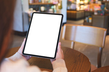 Mockup image of a woman holding digital tablet with blank white desktop screen in cafe