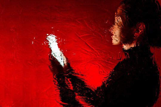 The silhouette looks at the smartphone in painterly red texture