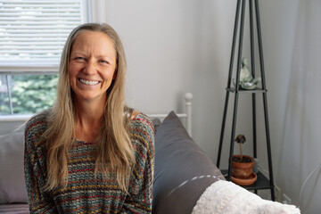 Smiling woman sitting indoors near a minimalist home decoration 