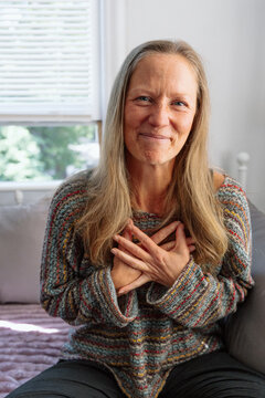 Smiling woman expressing gratitude with hands on her heart