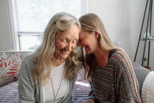 Elderly mother and adult daughter sharing a heartfelt laugh at home