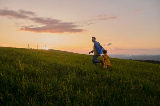 Father and Son Running Through Meadow at Sunset