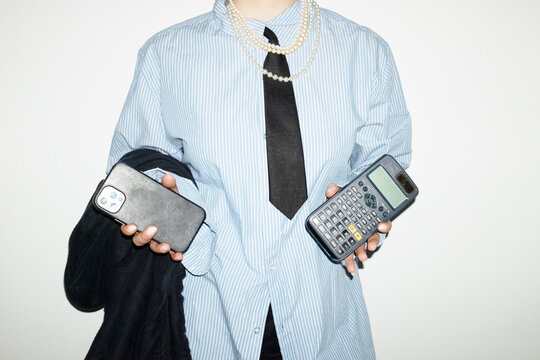 Person wearing suit, tie and shiny pearl necklaces in business office