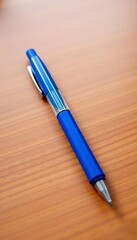 Disposable blue ballpoint pen lying on a wooden desk, ready for quick notes or signing,  simple,  essential