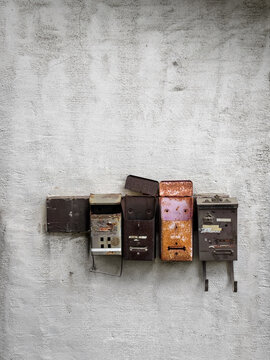 Rusty mailboxes on textured concrete wall