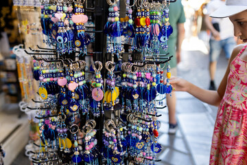 Kid looking at lucky key chains hanging at souvenir store in Athens.
