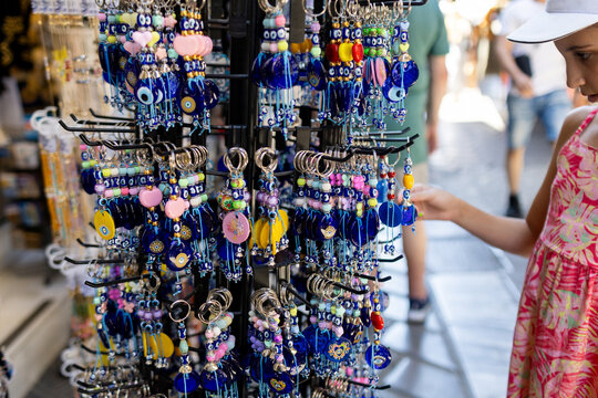 Kid looking at lucky key chains hanging at souvenir store in Athens.