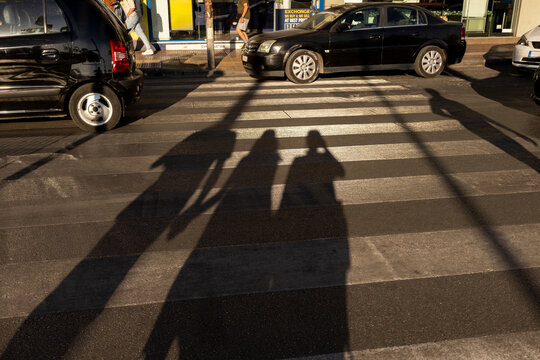 Shadow of family crossing street pedestrian cross in Athens city