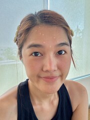 Happy Asian Thai woman smiling and sweating while taking selfie after done work out at gym.