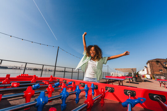 Excited woman celebrating while playing foosball outdoors