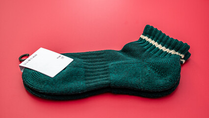Dark green knitted sock and white tag isolated on vibrant background.