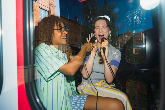 Friends singing and laughing in karaoke booth