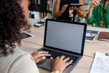 Woman types on laptop at meeting with invoice nearby.