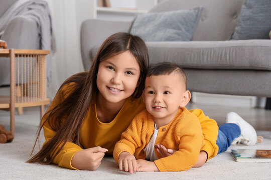 Teenage girl hugging her little brother on floor at home
