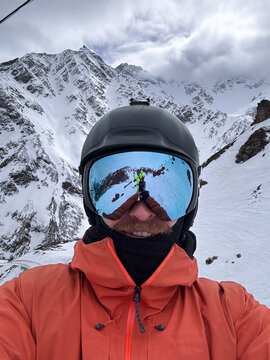 Snowy mountains reflected in ski goggles selfie